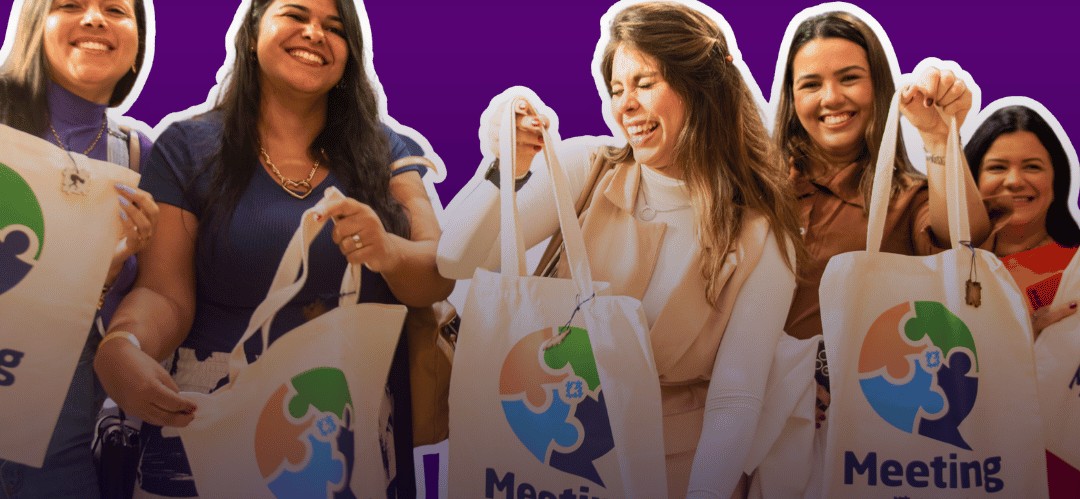 Participantes de uma edição anterior do Meeting, sorrindo com o brinde exclusivo do evento
