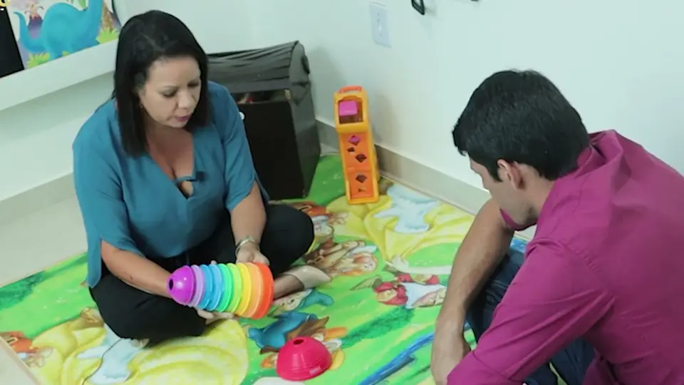 Fábio treina a AT Andreia no tapete, com um brinquedo de encaixe