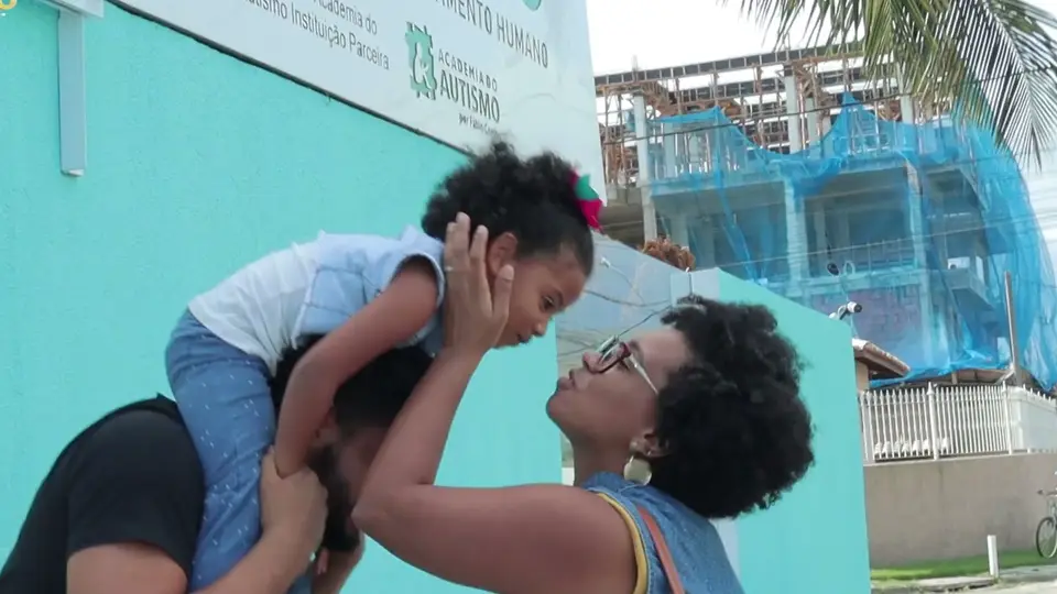 O pai carrega a filha nos ombros e a mãe sorri para ela