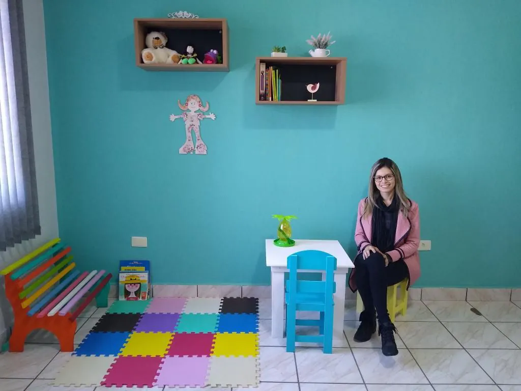 Aline Mediato sentada em uma sala de atendimento com paredes verdes