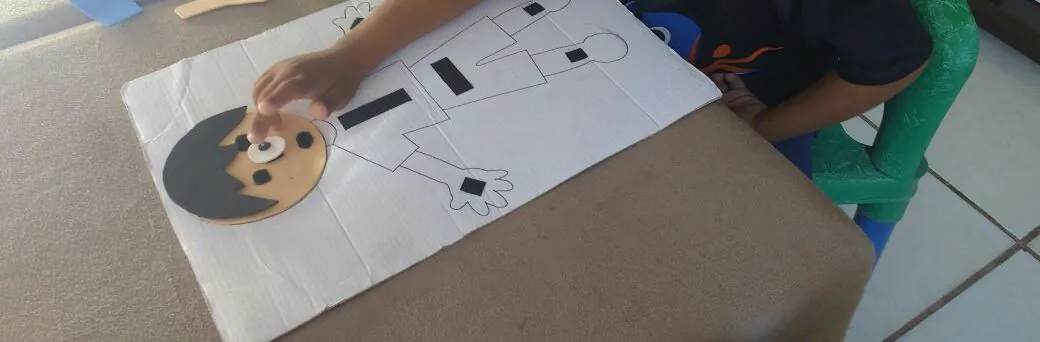 Criança montando as partes de um boneco em uma prancha