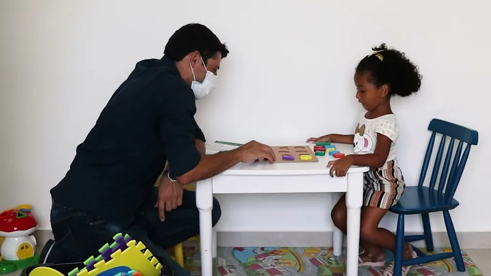 O coordenador Fábio Coelho brinca com a criança numa atividade com formas, durante a avaliação